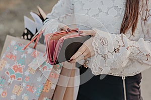 Woman with shopping bags holding a leather wallet