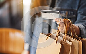 Woman with shopping bags holding and using a credit card for purchasing