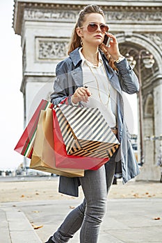 Woman with shopping bags near Arc de Triomphe using cell phone