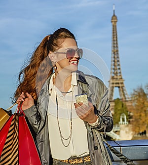 Woman with shopping bags and smartphone in Paris looking aside