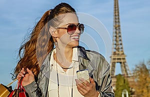 Woman with shopping bags and smartphone in Paris looking aside