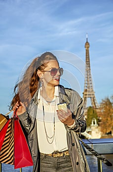 Woman with shopping bags and smartphone in Paris looking aside