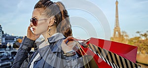 Woman with shopping bags speaking on mobile phone, Paris