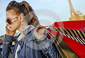 Woman with shopping bags speaking on mobile phone, Paris