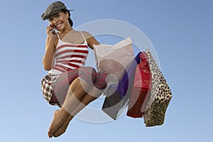 Woman With Shopping Bags Using Cell Phone In Midair