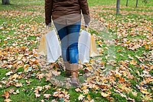 Woman with shopping bags walking along autumn park