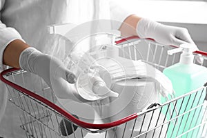 Woman with shopping basket full of antiseptics and toilet paper. Panic caused by virus