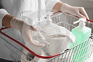 Woman with shopping basket full of antiseptics and toilet paper. Panic caused by virus