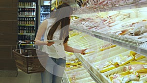 Woman with shopping cart buying refrigerated groceries at supermarket and using tablet pc to check shopping list. Girl