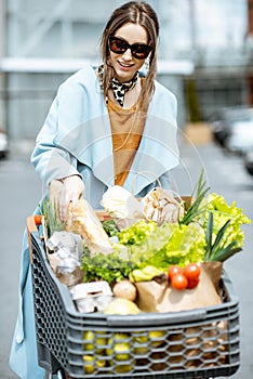 Woman with shopping cart full of food outdooors