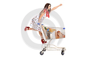 Woman with shopping cart full with products isolated over white background