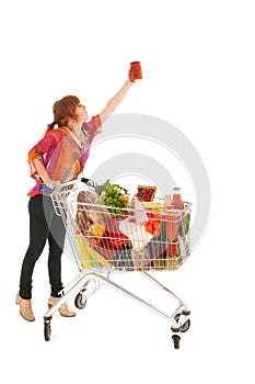 Woman with Shopping cart picking food from high cupboard