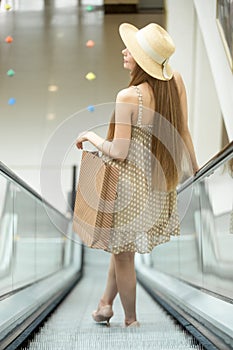 Woman in shopping centre riding on escalator. Back view