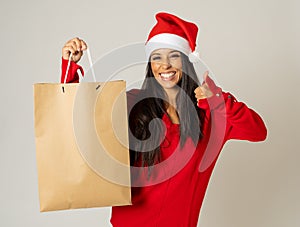 Woman shopping for christmas gifts with shopping bags and santa hat looking excited and happy