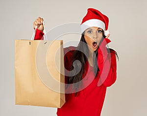 Woman shopping for christmas gifts with shopping bags and santa hat looking excited and happy