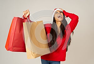 Woman shopping for christmas gifts with shopping bags and santa hat looking excited and happy