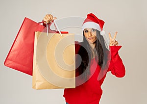 Woman shopping for christmas gifts with shopping bags and santa hat looking excited and happy