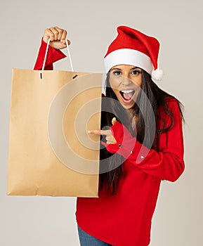 Woman shopping for christmas gifts with shopping bags and santa hat looking excited and happy