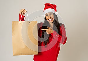 Woman shopping for christmas gifts with shopping bags and santa hat looking excited and happy