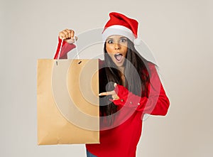 Woman shopping for christmas gifts with shopping bags and santa hat looking excited and happy