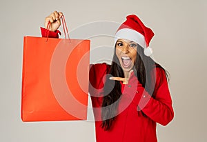 Woman shopping for christmas gifts with shopping bags and santa hat looking excited and happy