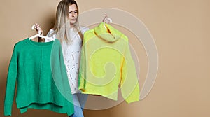Woman shopping Christmas sale choose between two sweaters blouse green and yellow happy smiling