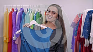 Woman shopping for dress in clothing retail store. Beautiful multiracial arabian Caucasian shopper girl choosing red