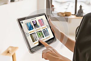 Woman shopping food online using a digital tablet at the kitchen, close-up view on a tablet screen. Concept of buying