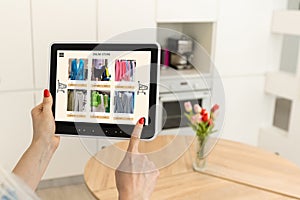 Woman shopping food online using a digital tablet at the kitchen, close-up view on a tablet screen. Concept of buying