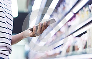 Woman shopping healthy food in supermarket background. Close up view girl buy products using digital gadget in store. Hipster