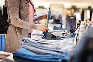 Woman shopping for jeans in fashion store.