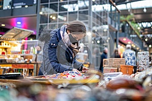 Woman shopping looking through jewellery on market stall wearing face mask protective during Covid 19 Coronavirus pandemic