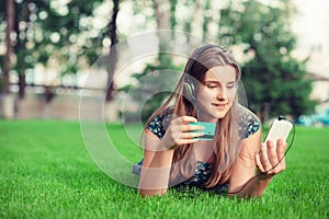 Woman shopping online with a credit card and phone with headphones outside