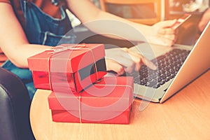 Woman shopping online using laptop with credit card and red gift