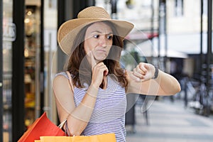 woman in shopping street looking at time on wristwatch