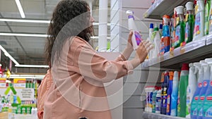 woman is shopping in supermarket, choosing cleaning products for home cleanup