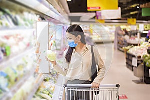 Woman is shopping in supermarket with face mask