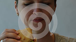 Woman with short haircut eating hamburger sitting in fast food cafe. Girl enjoys burger with chicken cutlet, vegetables