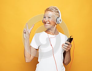 woman with short white hair wearing white tshirt listening to music with headphones