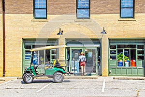 Woman in shorts and hat locking up art studio with ATV parked outside - rear view with reflections in windows