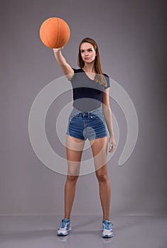 Woman in shorts holding foot ball on gray background