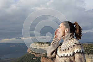 Woman shouting in the mountain in winter holiday