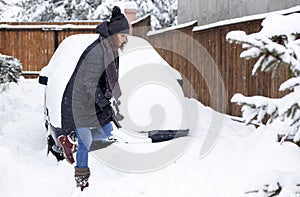 woman with shovel cleaning snow aeound car. Winter shoveling. Removing snow after blizzard