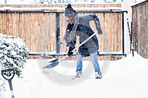 woman with shovel cleaning snow around car. Winter shoveling. Removing snow after blizzard