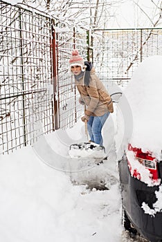 Woman shoveling snow around car