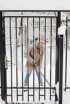 Woman shoveling snow by fence