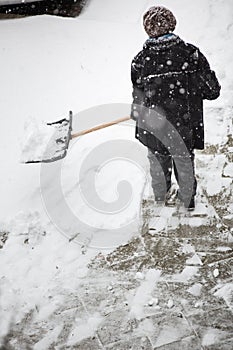 Woman shoveling snow from the sidewalk in front of his house