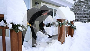 Woman shovels snow from the entry way to a winter cabin