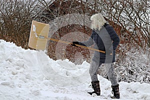 A woman shovels snow in winter. Snow shovels during snowfall