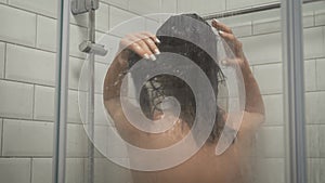 Woman in the shower, back side of young female showering under refreshing water, healthy lifestyle. Girl washing long